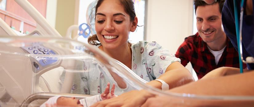 Mother and father visiting her newborn child in maternity ward