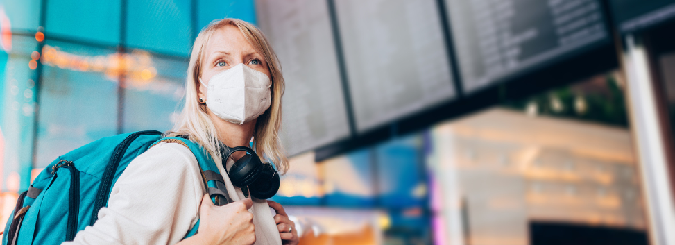 Woman wearing backpack with mask on in airport.